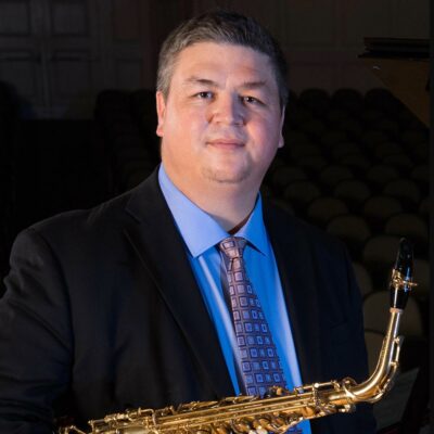 headshot photo of Adam Estes holding saxophone